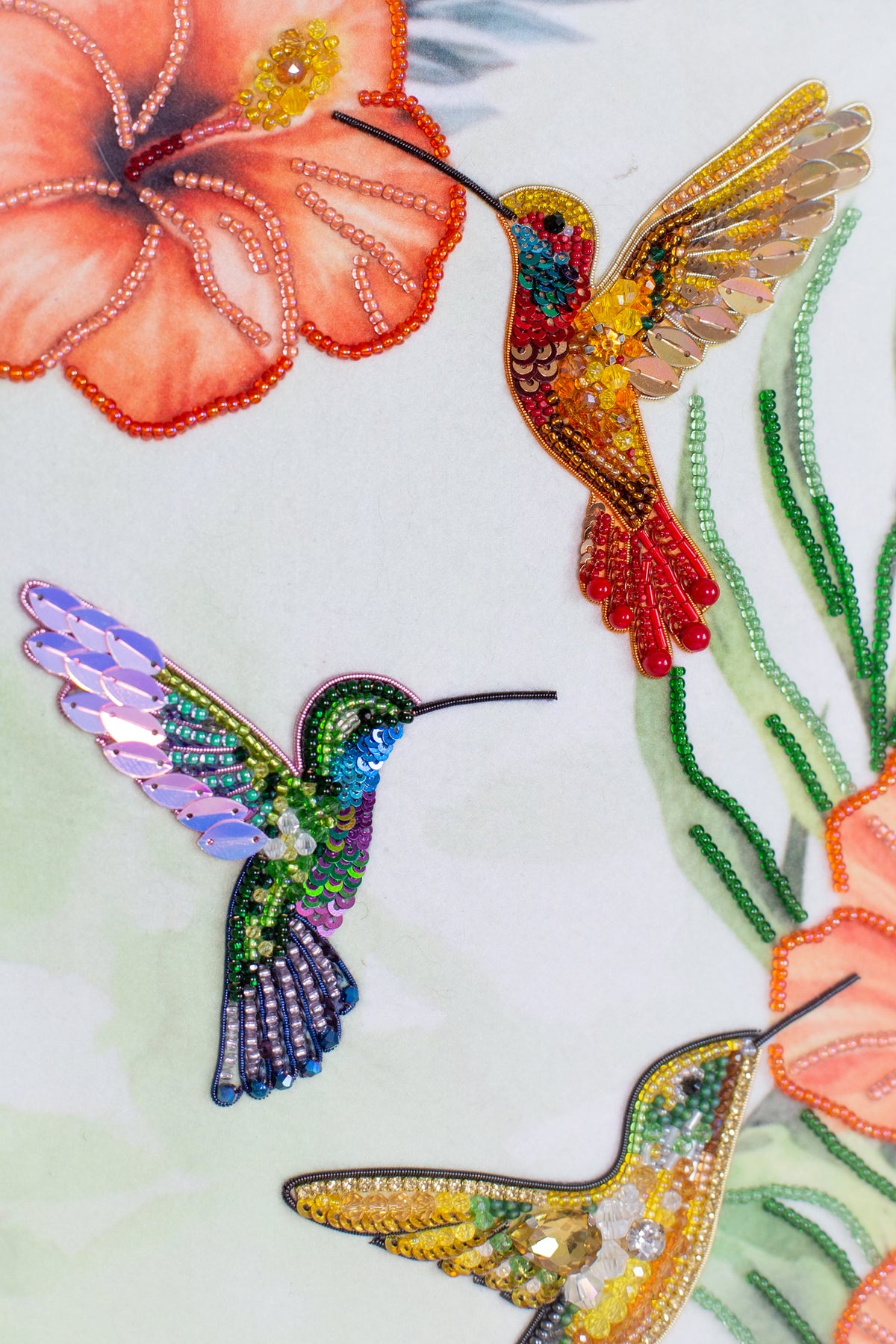 three colorful hummingbirds, each with distinct colors and patterns, against a light green background.