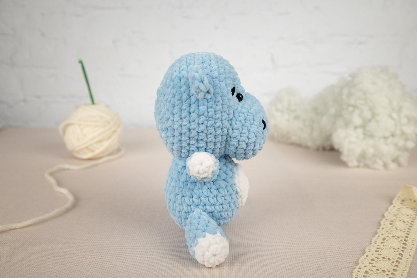 a crocheted blue elephant sitting next to a ball of yarn