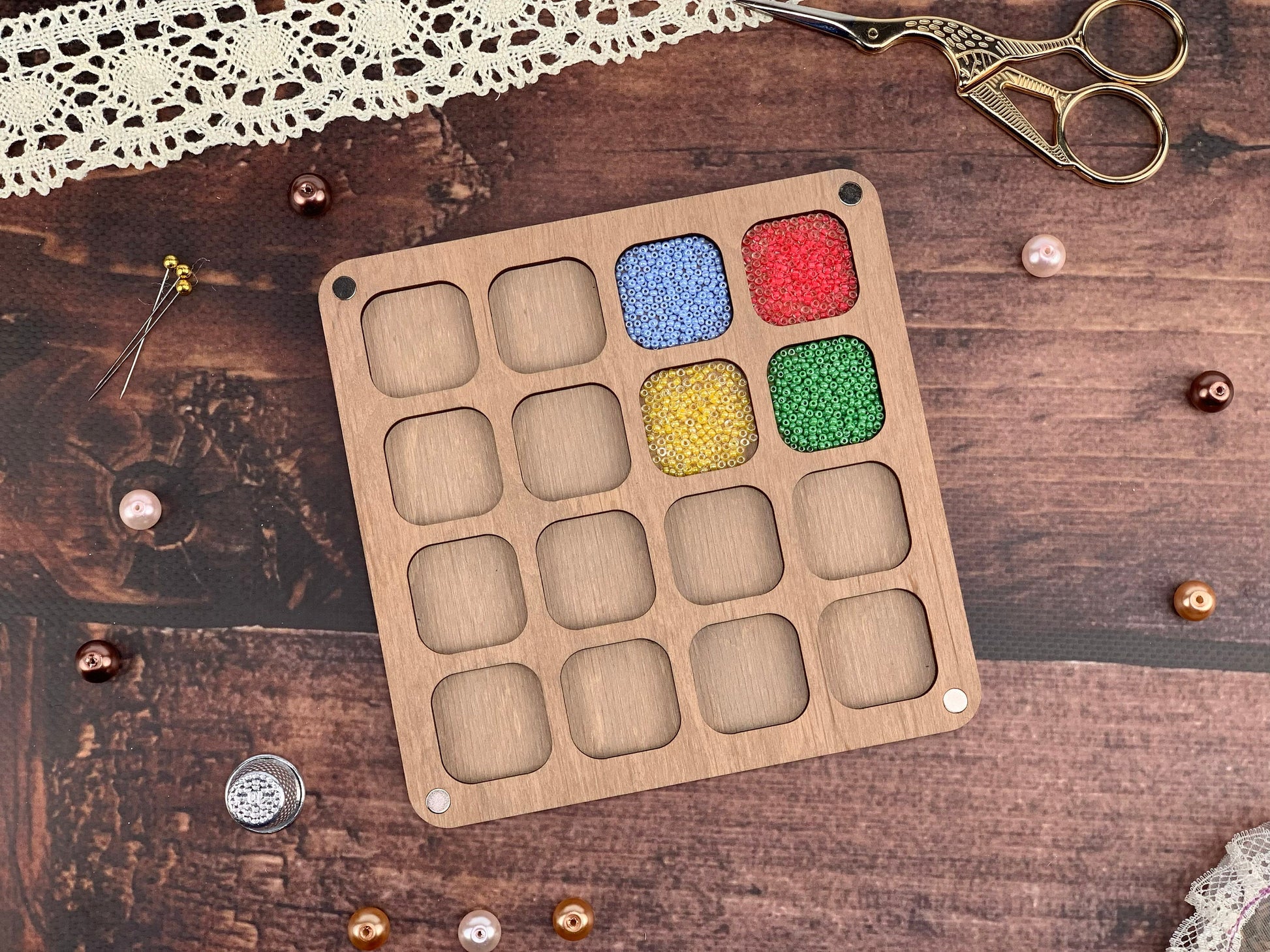 a wooden tray with beads and a pair of scissors