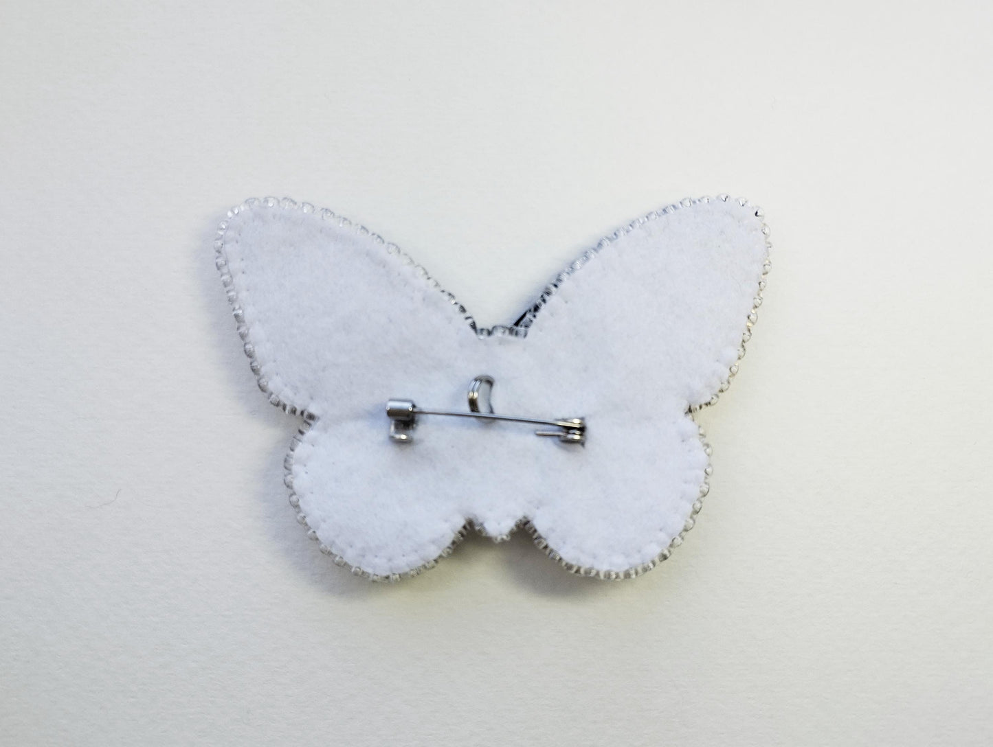 a white butterfly brooch with a pin on it