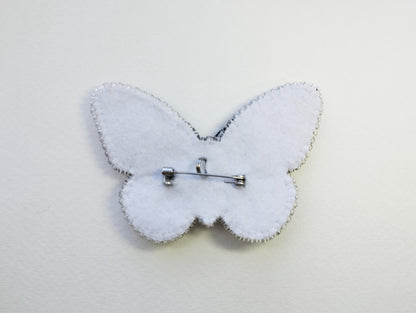 a white butterfly brooch with a pin on it