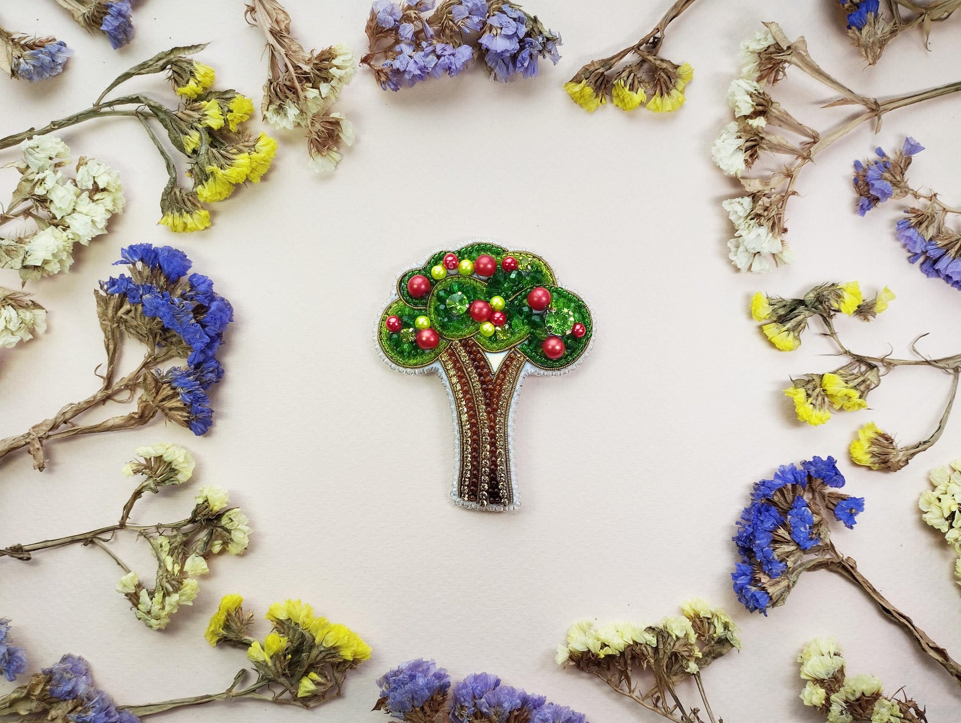 a brooch with a tree on it surrounded by flowers