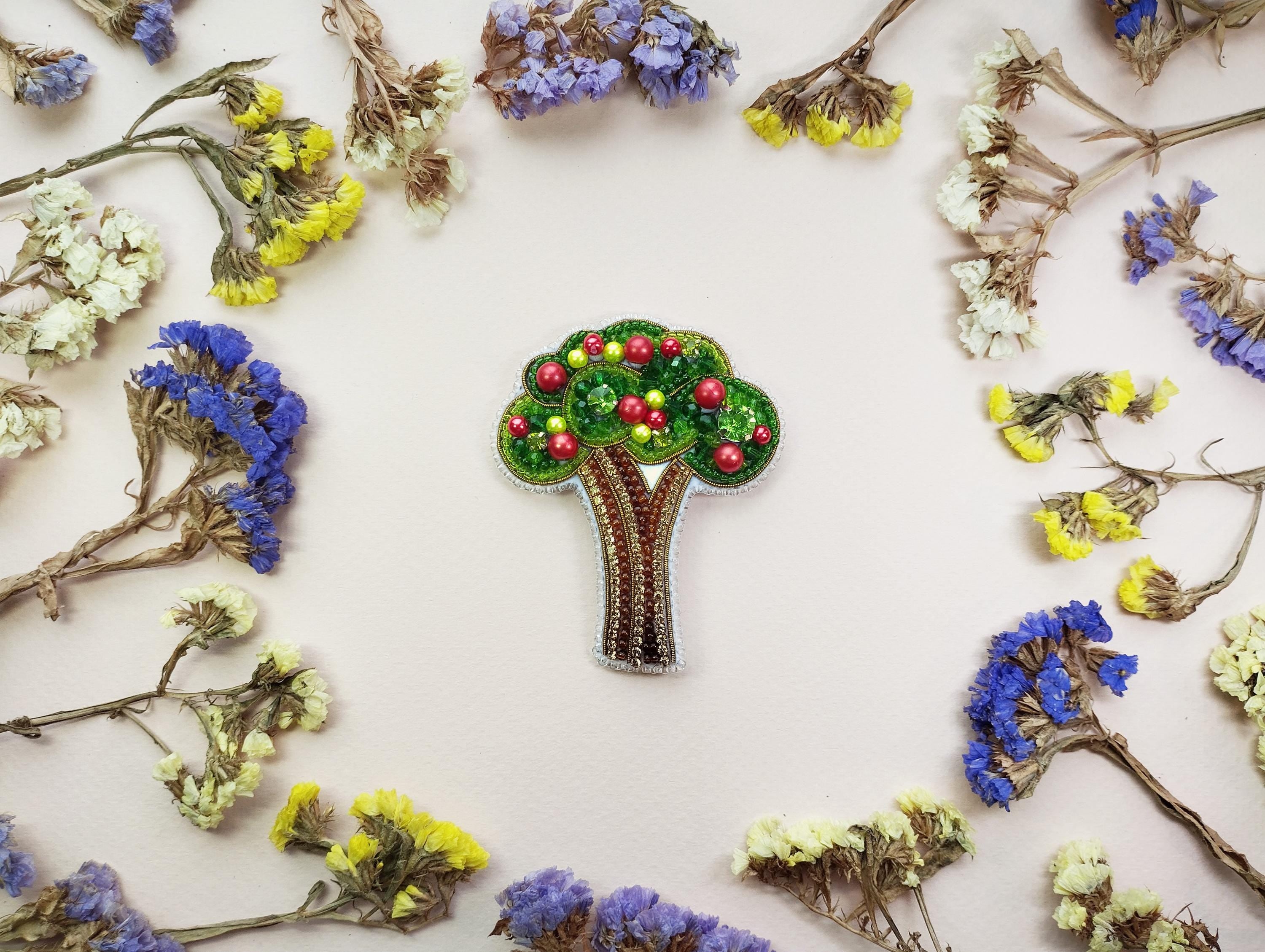 a brooch with a tree on it surrounded by flowers