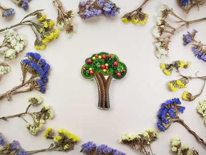 a brooch with a tree on it surrounded by flowers