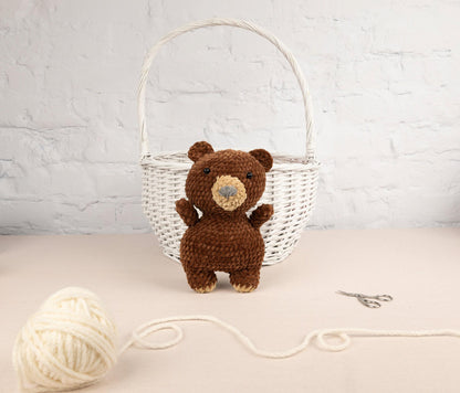 a brown teddy bear sitting next to a ball of yarn