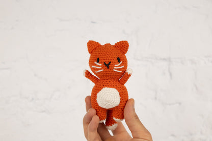 a hand holding a small crocheted cat
