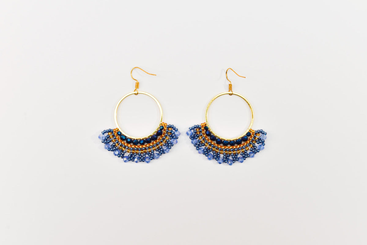 A pair of gold hoop earrings with blue and gold beads hanging from the bottom.