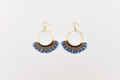 A pair of gold hoop earrings with blue and gold beads hanging from the bottom.
