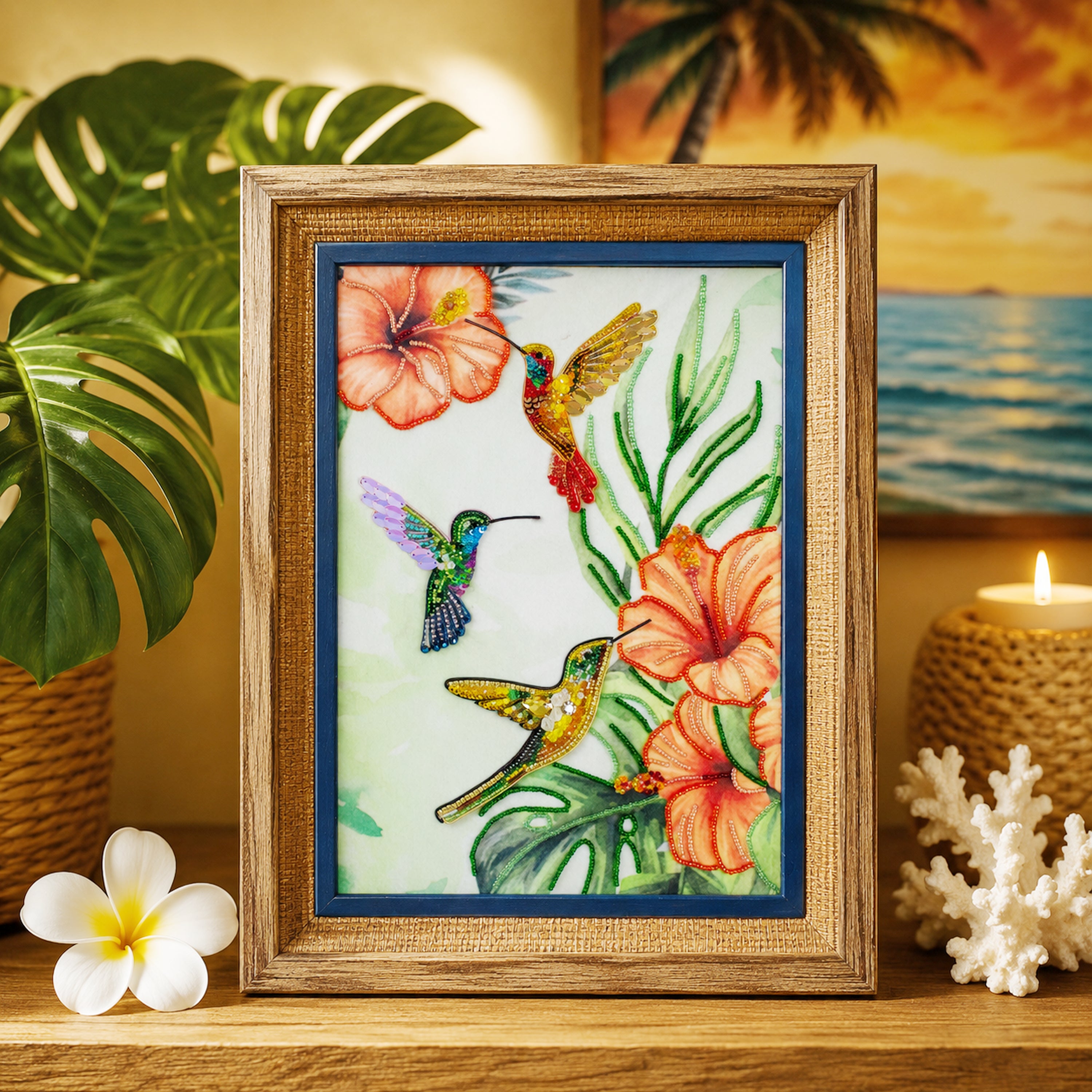 A framed painting of three colorful hummingbirds surrounded by tropical flowers, including hibiscus blooms, is displayed on a wooden shelf.
