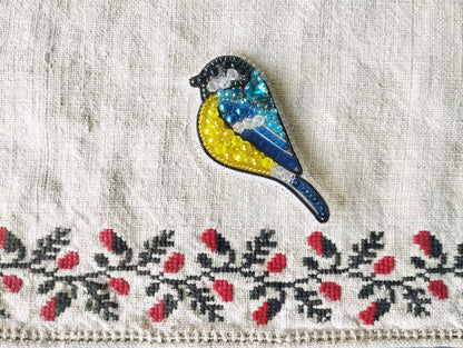 a blue and yellow bird sitting on top of a white cloth