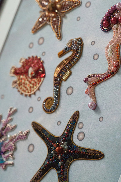 a close-up view of various sea-themed embellishments, including a starfish, a seahorse, and a pufferfish, all intricately designed with beads and other decorative elements.