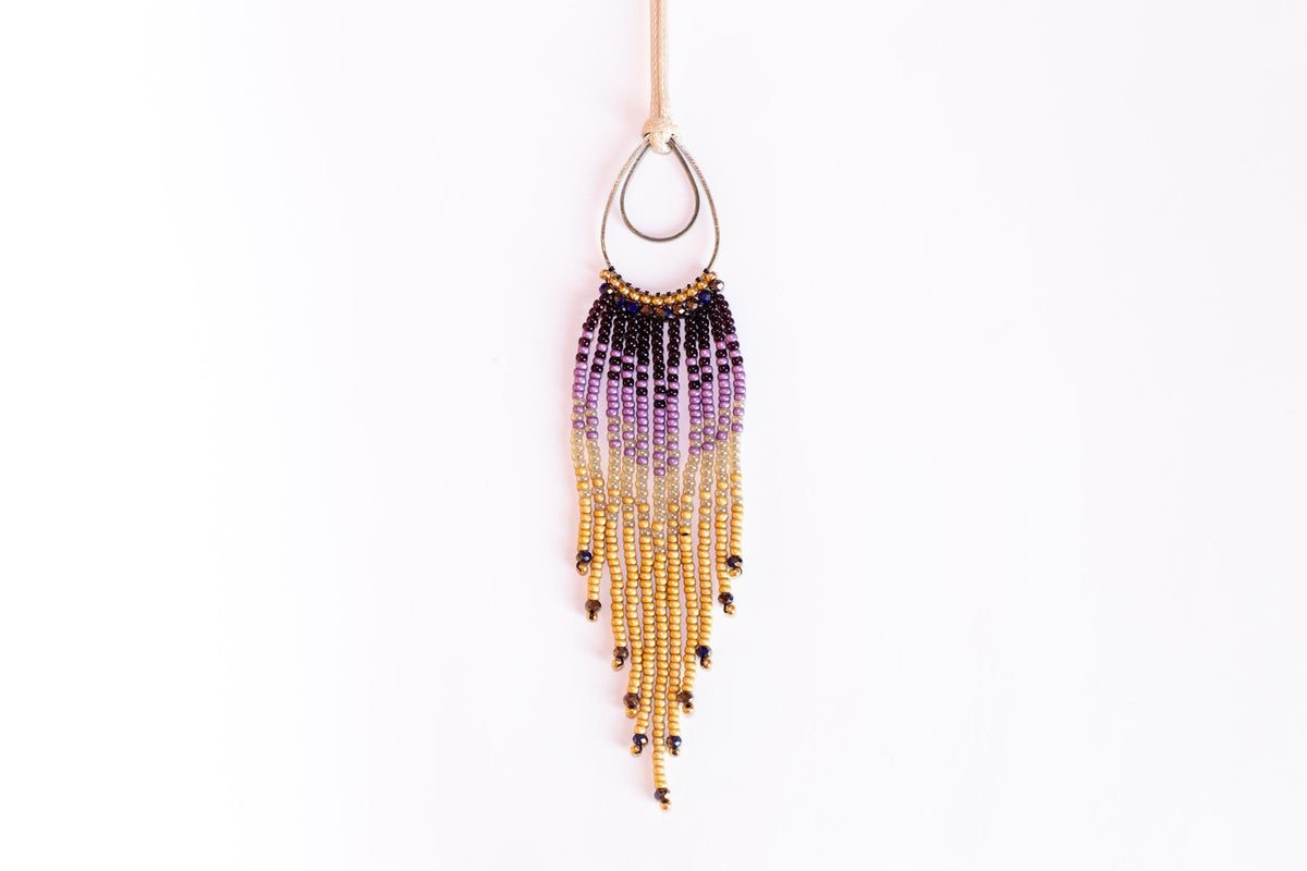 A beaded earring with a long, tassel-like fringe hanging from a hook against a white background.