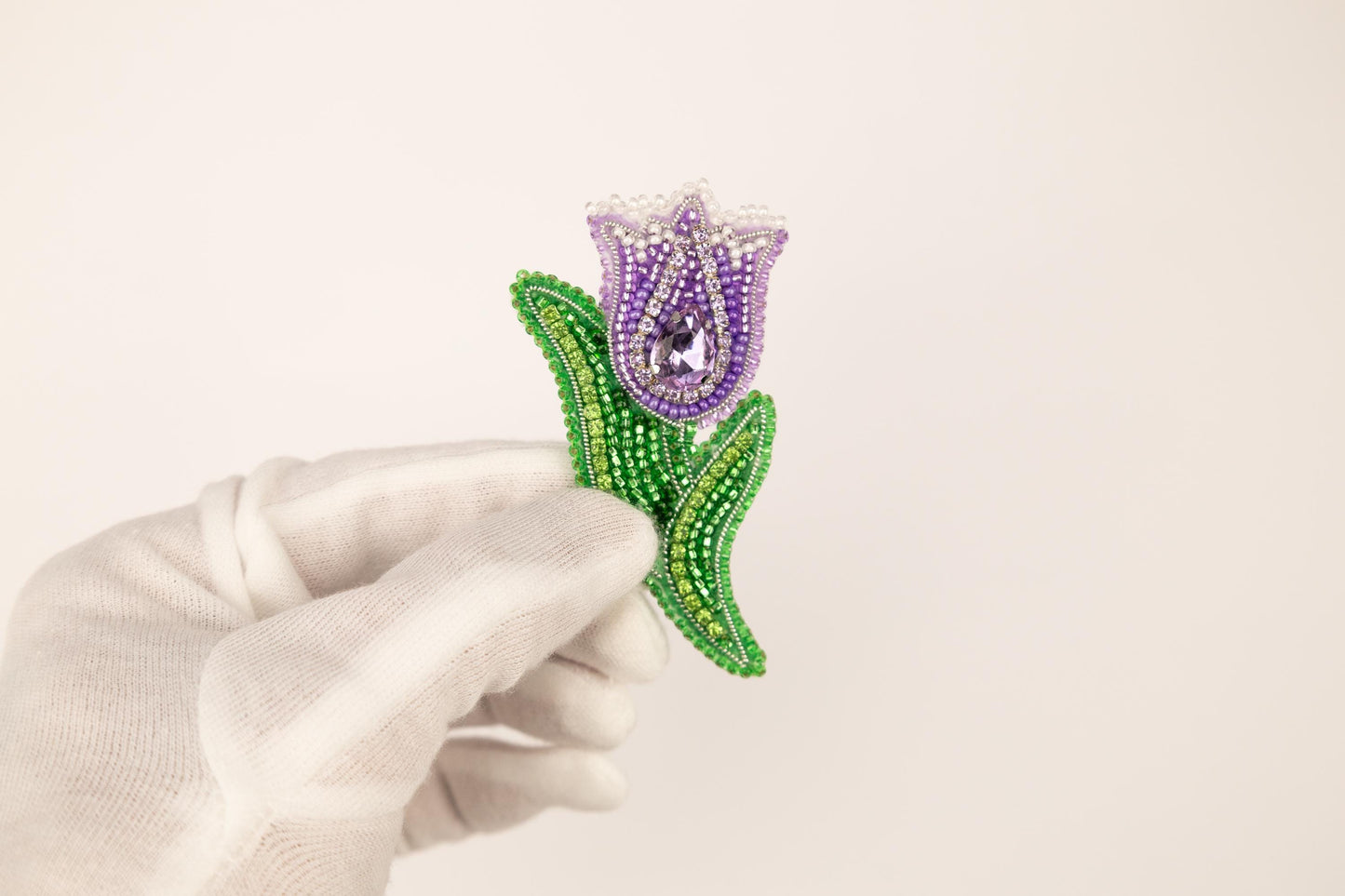 a person in white gloves holding a beaded flower