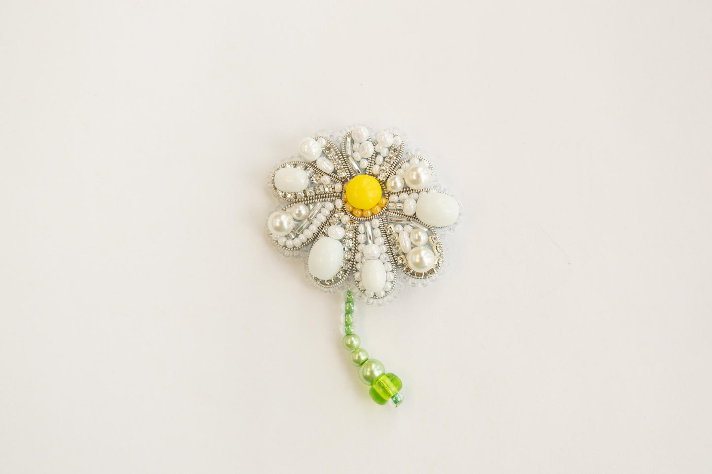 a white and yellow flower brooch with beads