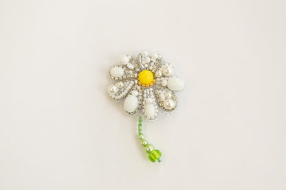 a white and yellow flower brooch with beads