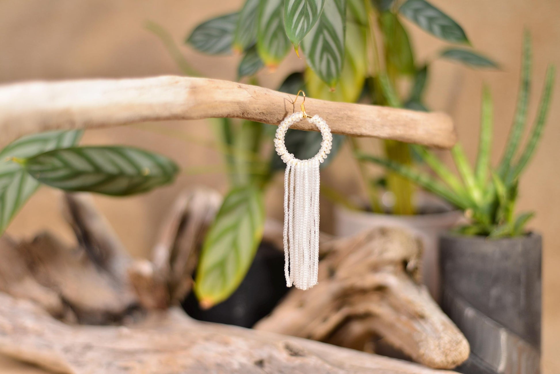 a small white beaded tassel hanging from a tree branch