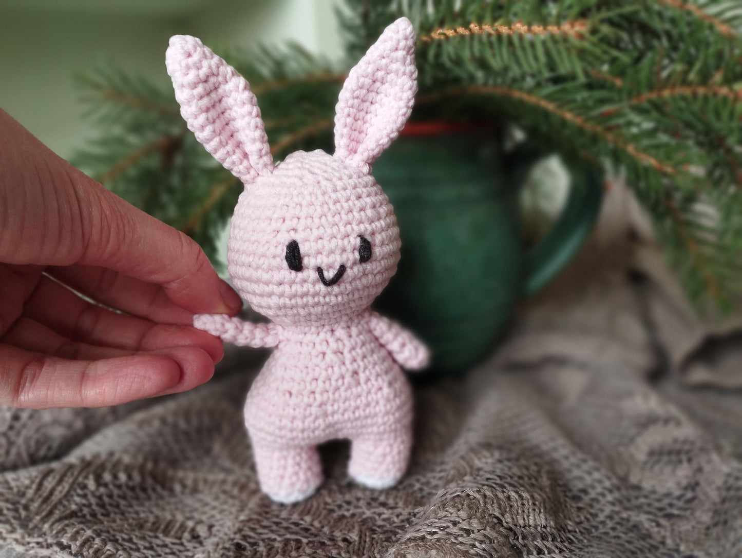 a small crocheted bunny sitting next to a christmas tree
