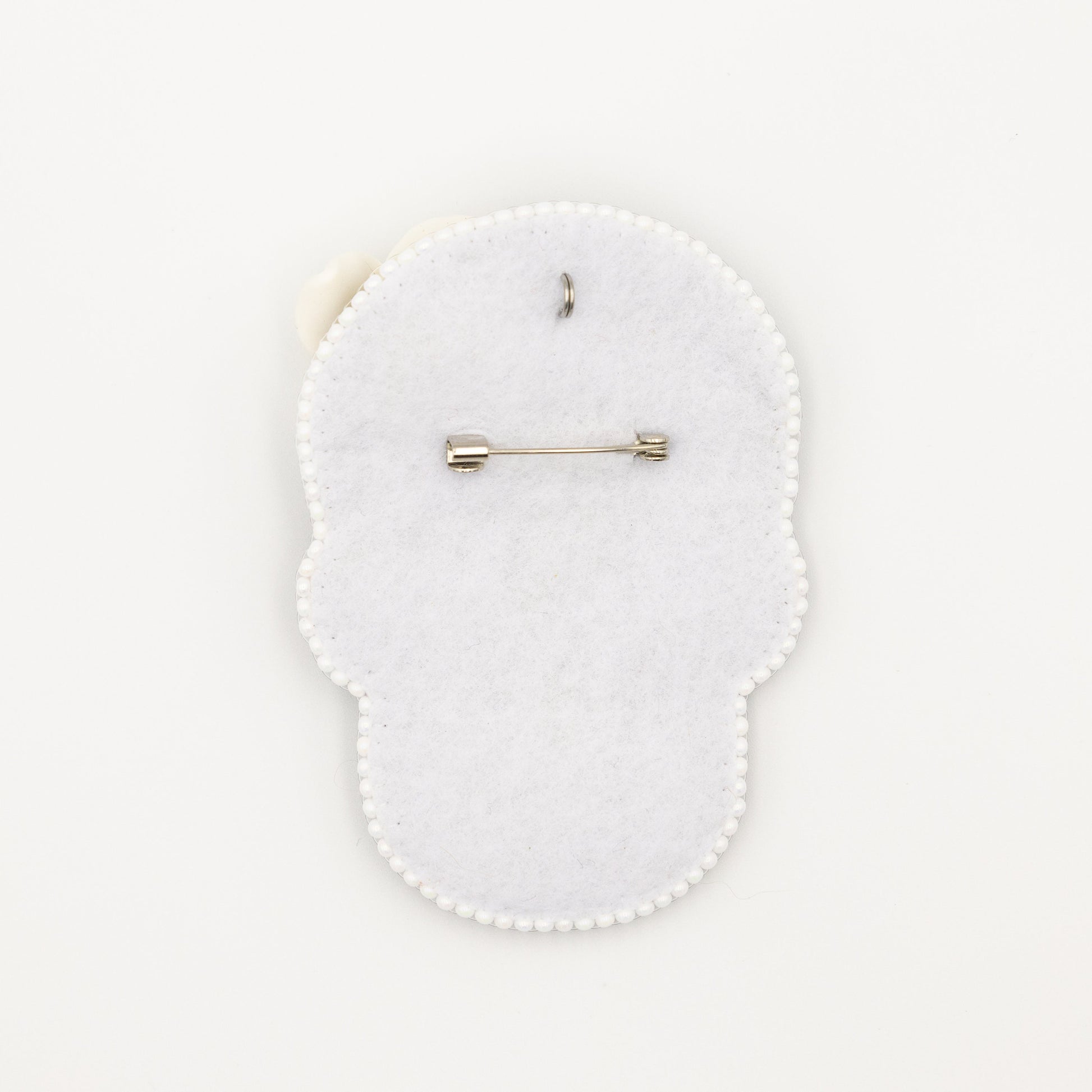 a white brooch with a pin on it