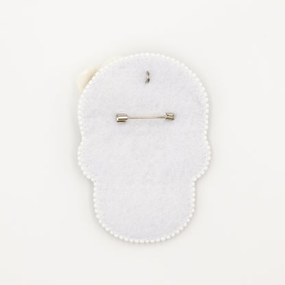 a white brooch with a pin on it