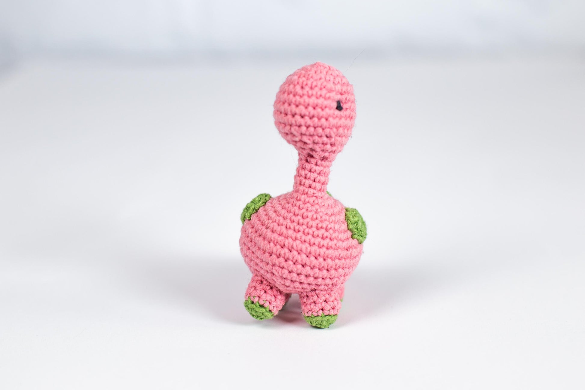 a pink crocheted turtle sitting on top of a white table