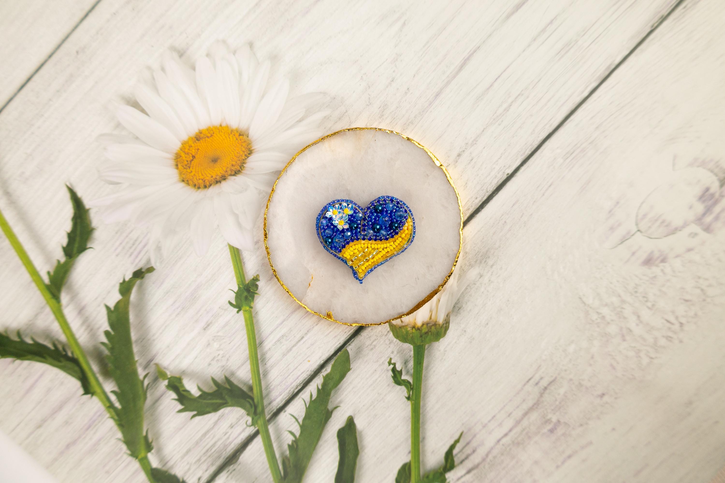 a flower and a heart shaped brooch sitting on a table