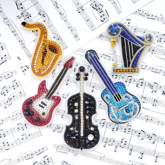 a collection of musical instruments, including a saxophone, a harp, a guitar, and a violin, all adorned with sparkling rhinestones or beads. The instruments are arranged on a sheet of music, creating a visually appealing and harmonious composition.