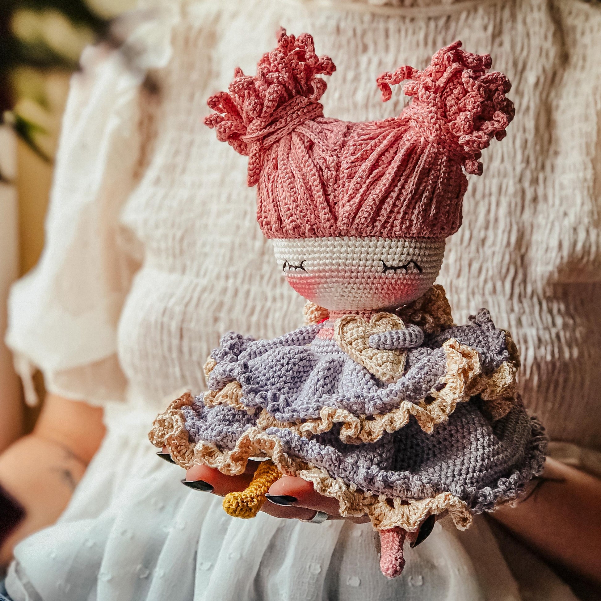 a knitted doll wearing a pink hat and dress