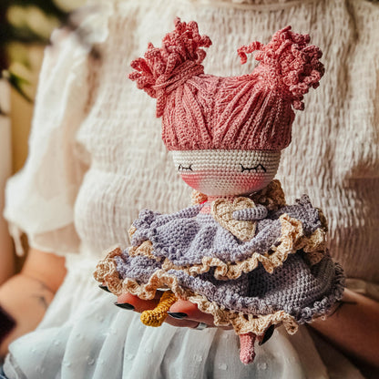 a knitted doll wearing a pink hat and dress