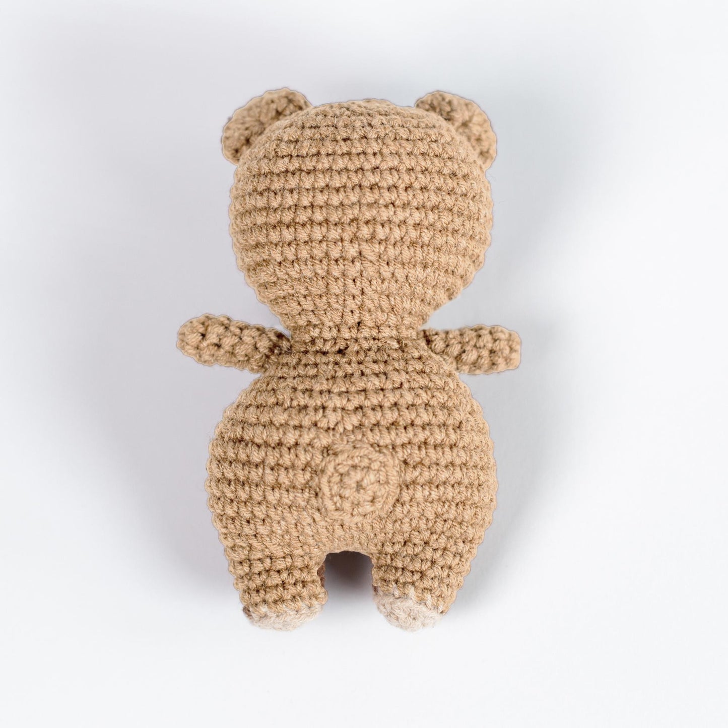 a crocheted teddy bear sitting on a white surface