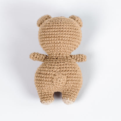 a crocheted teddy bear sitting on a white surface