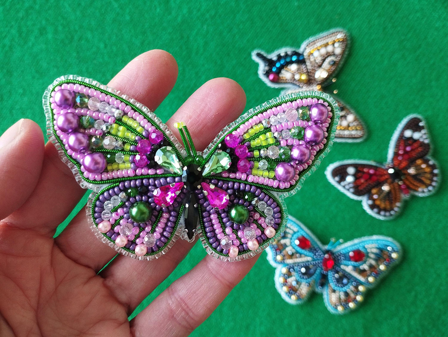 a hand is holding a colorful butterfly brooch