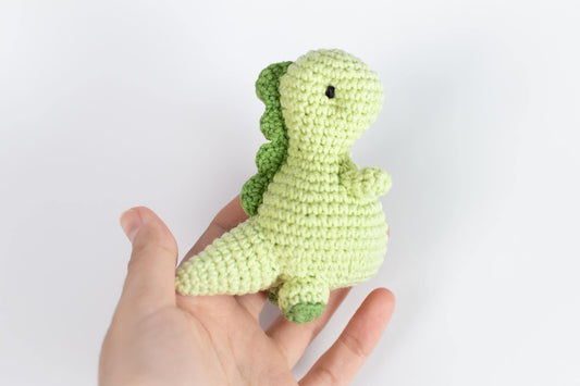 a hand holding a small crocheted stuffed animal