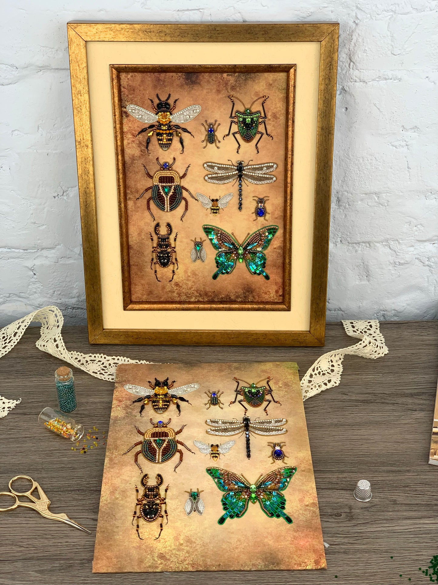 a framed print of various insects, including bees, butterflies, and dragonflies, along with some crafting supplies and materials on a wooden surface.