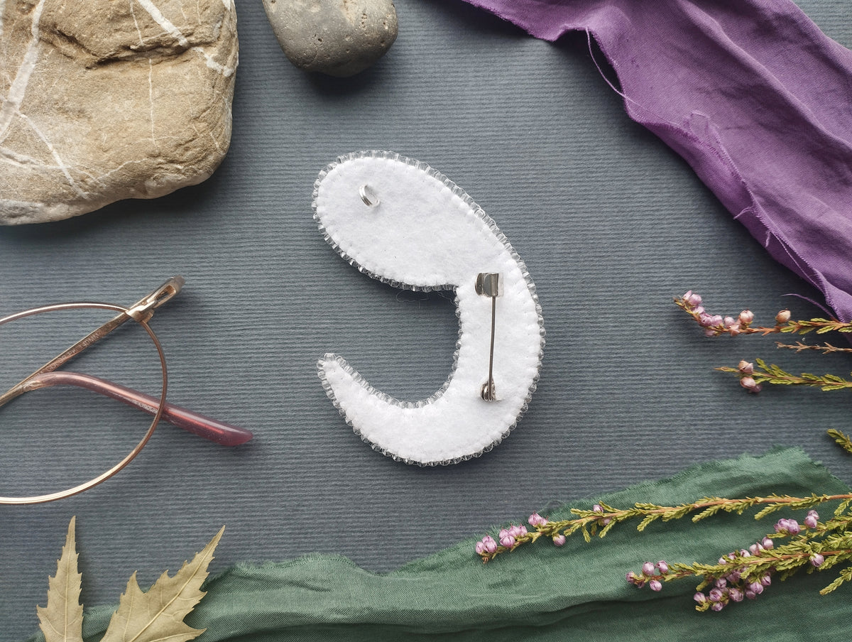 a close-up view of various objects, including a pair of glasses, a rock, a piece of fabric, and some flowers, all arranged on a grey background.