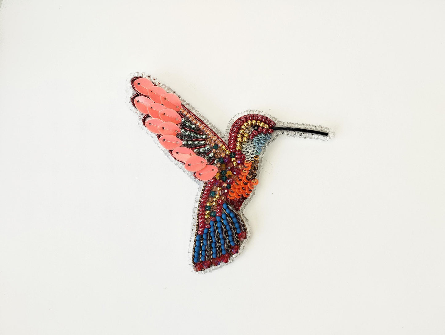 a colorful bird made out of beads on a white surface