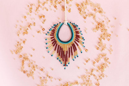 a beaded necklace with a large, colorful pendant, surrounded by scattered beads in various shades of gold, red, and blue.