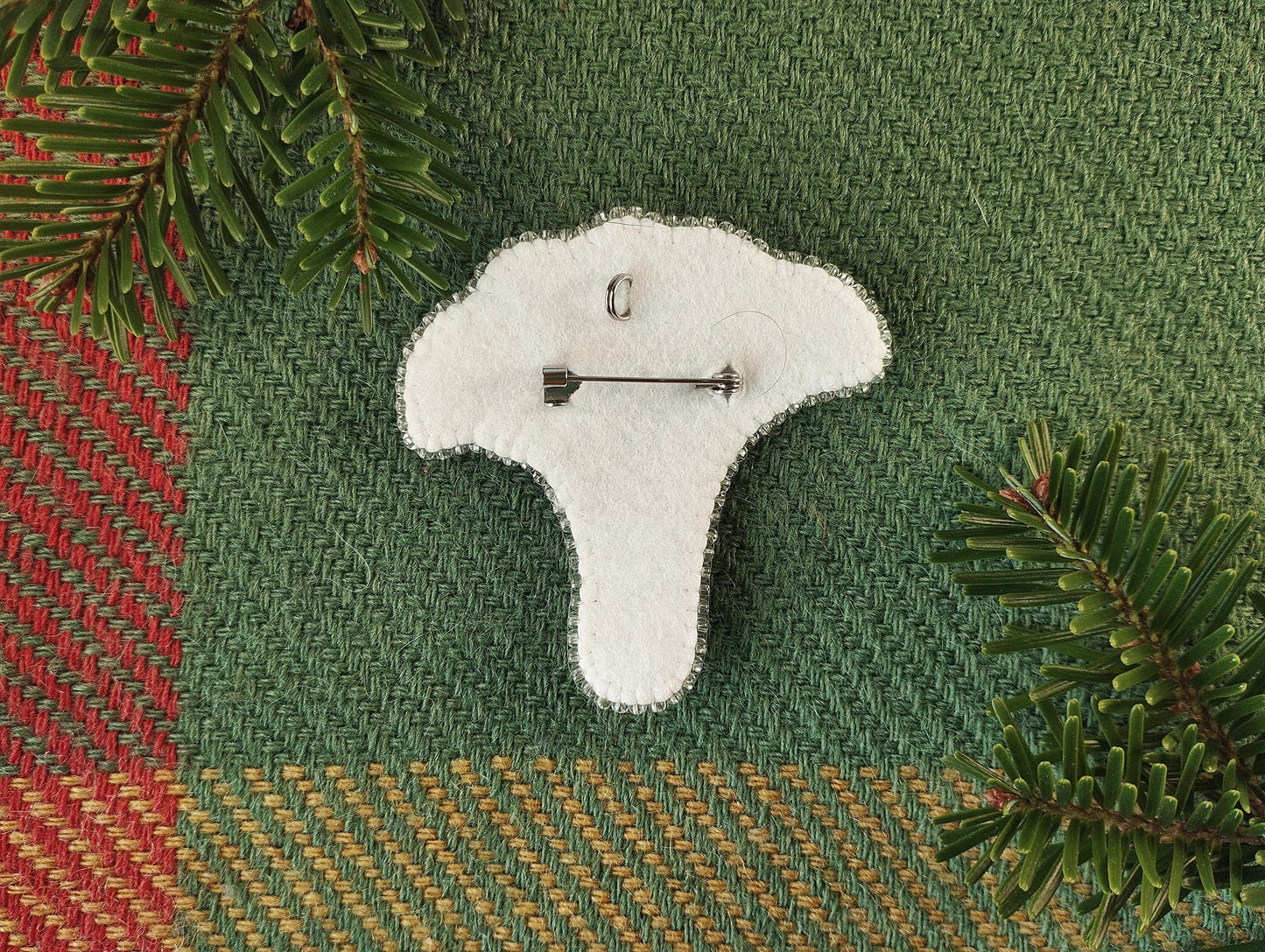 a white brooch with a needle on it