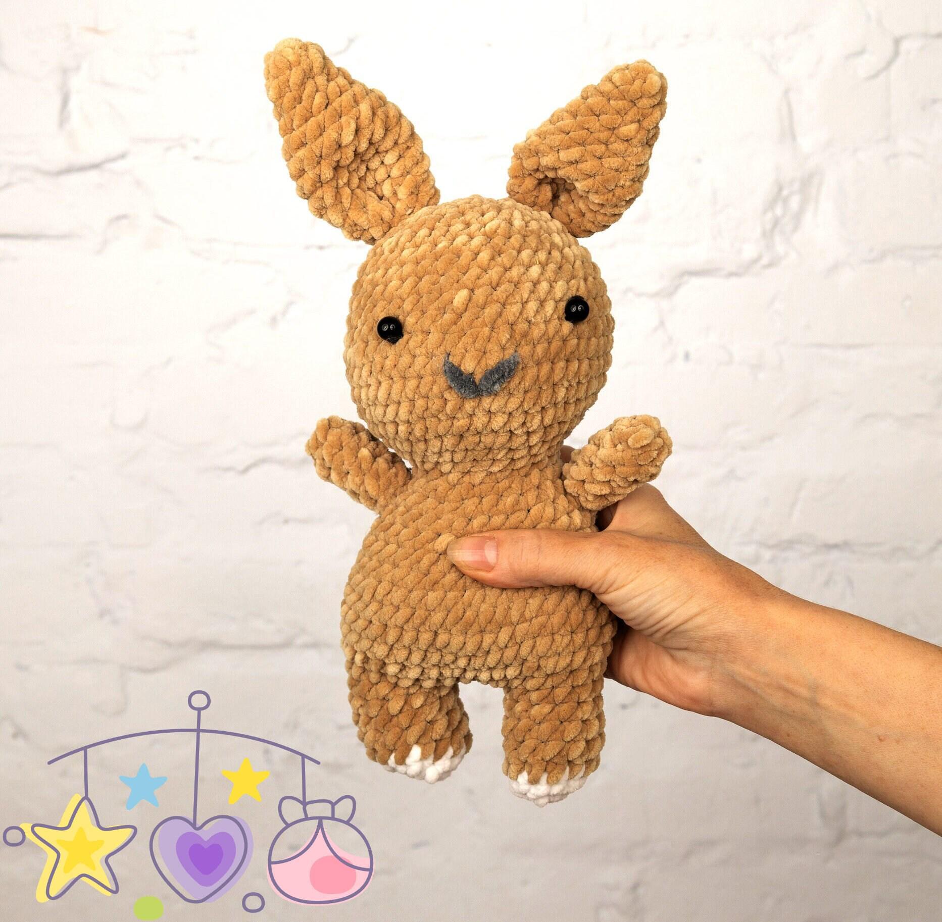 a small stuffed rabbit sitting in a basket next to a ball of yarn