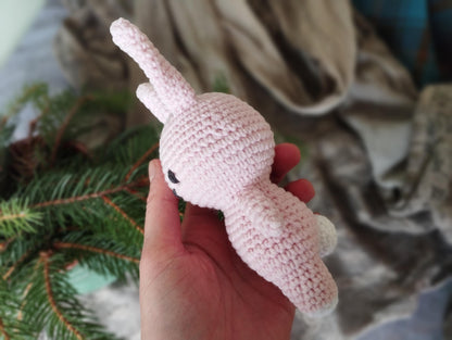a hand is holding a small crocheted stuffed animal
