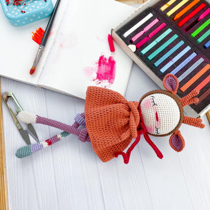 a crocheted doll next to a crayon crayon set and