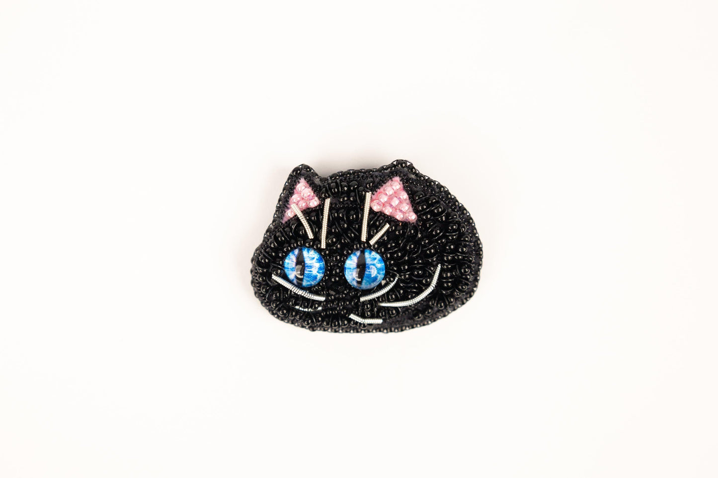 a black cat brooch with blue eyes and pink bows