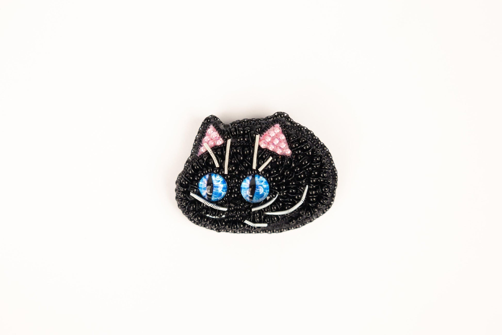 a black cat brooch with blue eyes and pink bows