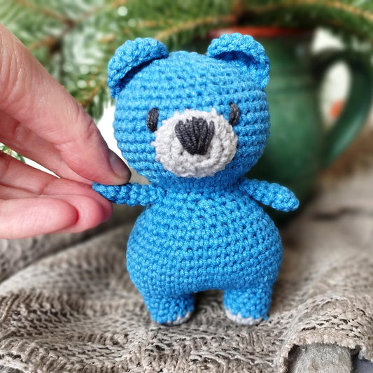 a crocheted blue teddy bear sitting on top of a table