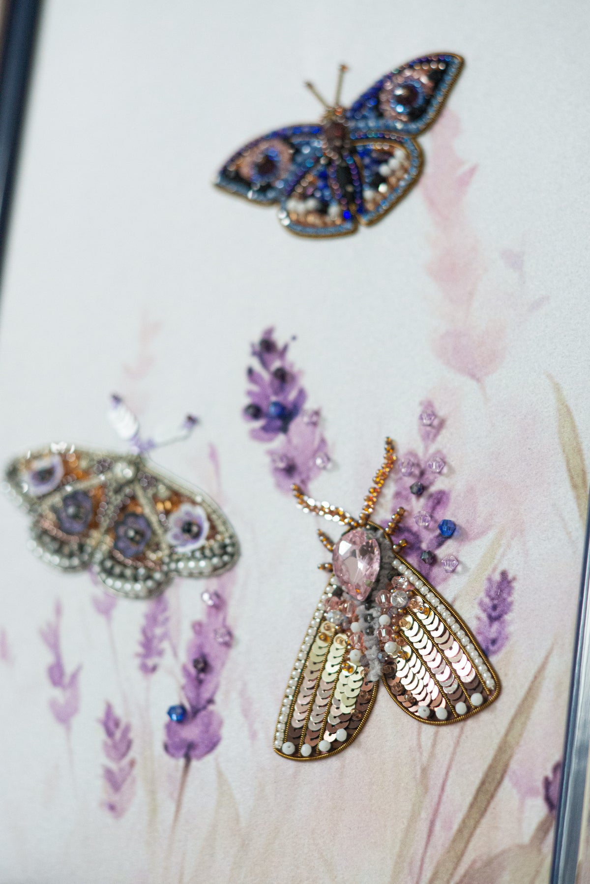 three butterflies with intricate designs and embellishments, including jewels and flowers, set against a background of purple flowers.