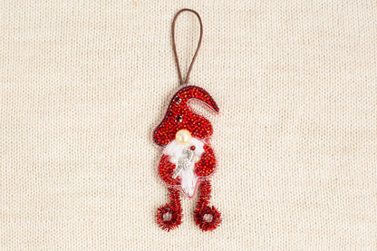 A red ornament resembling a gnome or gnome-like figure is hanging on a beige background.