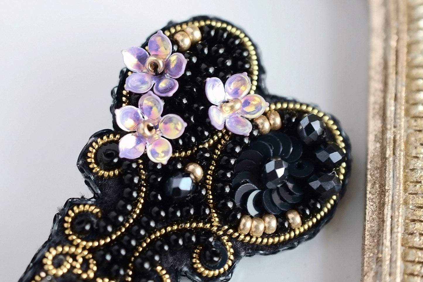 a black and gold brooch with flowers on it