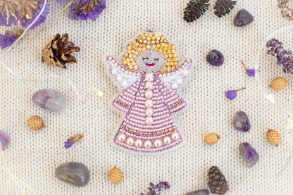 a decorative angel figure made of beads and surrounded by various natural elements, such as pine cones, gemstones, and flowers.