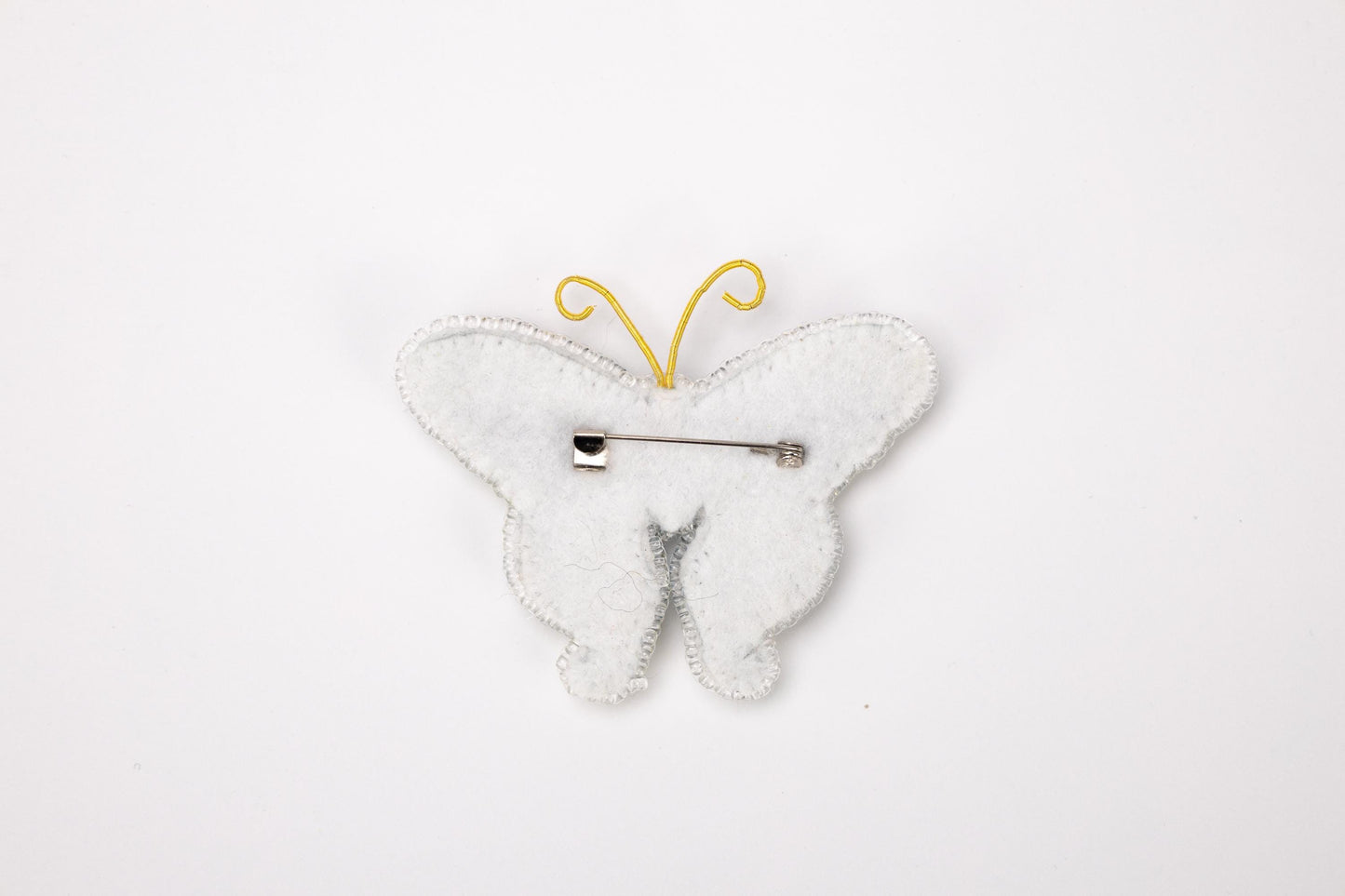 a white butterfly shaped brooch with a hair pin