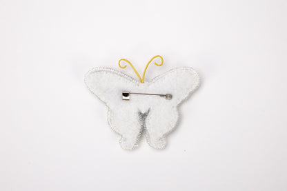 a white butterfly shaped brooch with a hair pin