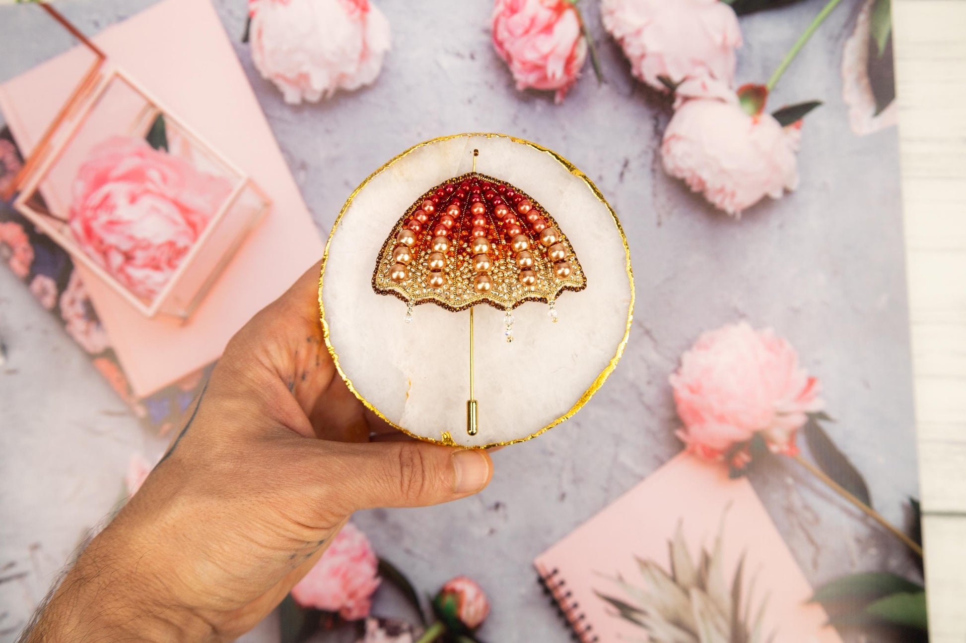 a hand holding a cupcake decorated with an umbrella